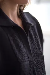 Vestido corto negro con cuello polo y detalle de calados en el ruedo y en la parte superior.