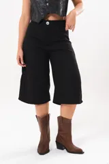 Bermuda de tiro medio y silueta amplia en color negro, con bolsillos delanteros y traseros, y cierre frontal con cremallera y botón.