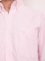 Camisa de corte regular confeccionada en algodón, con diseño de rayas verticales en tonos azul y blanco. Presenta cuello con botones, cierre frontal abotonado, bolsillo en el pecho con logo bordado y mangas largas.