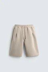 Bermuda de corte oversize confeccionada en tejido técnico compacto con elasticidad. Presenta cintura elástica ajustable con cordón, pinzas en el delantero y la espalda, y bolsillos laterales.