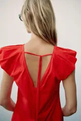 Top rojo de popelín con escote en V pronunciado, mangas sisa y pespuntes en contraste. Cuenta con tirantes finos cruzados y lazada en la espalda.