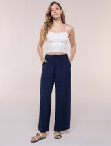 Pantalón azul marino de pernera ancha, confeccionado en tela con textura gofrada y ligera. Cuenta con tiro alto, pretina elastizada con cordón ajustable, bolsillos frontales aplicados y corte fluido.