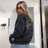 Buzo de cuello redondo Eseele Club Stone con acabado stonewash en color negro lavado, corte oversize y diseño relajado. Presenta logo ovalado retro en la espalda y terminaciones acanaladas.