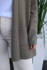 Saco tipo cárdigan abierto de punto fino en color verde oliva, con mangas largas y bolsillos frontales aplicados.