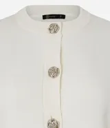 Cardigan de punto color negro, con cuello redondo, mangas largas y cierre frontal mediante botones metálicos con diseño de flores. Presenta puños y ruedo acanalados.