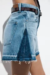 Shorts de jean de tiro medio, corte mom fit, con efecto lavado y terminación desflecada. Presenta cinco bolsillos y cierre frontal con cremallera y botón.