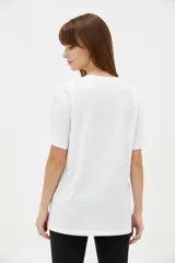 Remera de algodón negra de manga corta y cuello redondo, con estampa frontal que incluye letras rojas y gráficos en tonos dorados.