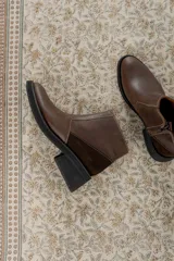 Bota corta de cuero marrón con panel trasero de gamuza en tono más oscuro, suela de goma negra y taco cuadrado bajo.