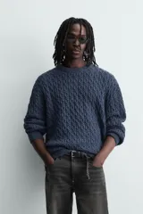 Jersey de punto con diseño de trenzas, cuello redondo y manga larga. Presenta un ajuste oversized y acabados en rib en puños y ruedo.