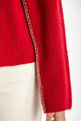 Sweater de lana color rojo, con cuello redondo, mangas largas y detalle de costura decorativa en los laterales.