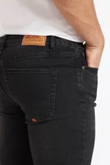 Pantalón jeans Quiksilver modelo RIN para hombre, de corte slim y color negro gastado, con bolsillos clásicos y cierre frontal de botón y cremallera.