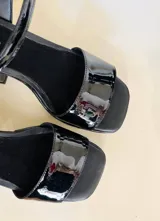 Sandalias de cuero charol negro con plataforma delantera y taco cuadrado.
