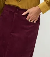 Pollera midi de gamuza sintética color bordó, con cintura alta, bolsillos laterales y tajo central delantero.