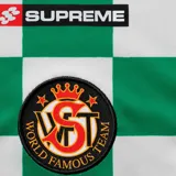 Camiseta de fútbol Supreme con diseño de tablero de ajedrez en verde y blanco, paneles laterales con estampado de camuflaje tipo realtree, cuello en V y número 8 estampado en el frente.