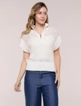 Buzo de punto color marfil, confeccionado en algodón calado con cuello alto acanalado y medio cierre metálico dorado. Presenta mangas cortas estilo japonesa con puños anchos y un zócalo acanalado en el ruedo.