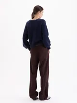 Pantalón de corte recto confeccionado en tela sastrera, con cintura de cuero vacuno, raya marcada en el centro de las piernas y bolsillos laterales.