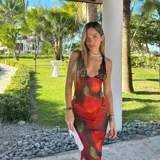 Vestido midi de microtul rojo con estampado de rosas y hojas verdes, escote en V con encaje negro y breteles finos regulables en la espalda.