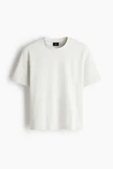 Remera de corte holgado confeccionada en punto interlock de algodón, con cuello redondo acanalado y hombros caídos.