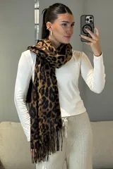 Bufanda rectangular con estampado animal print de leopardo en tonos marrones y negros, con terminación de flecos en los extremos.