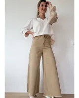 Pantalón de jean color beige, de corte recto y tiro alto, con ruedo deshilachado y cierre frontal con botón y cremallera.