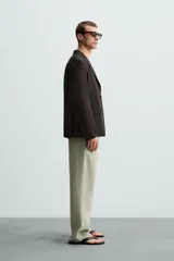 Blazer regular fit color marrón oscuro confeccionado en tejido de lino. Tiene cuello con solapas de muesca, manga larga con puño abotonado, bolsillo de vivo en el pecho, bolsillos de solapa en la cadera, bolsillo interior, bajo con aberturas en la espalda y cierre frontal con botonadura.