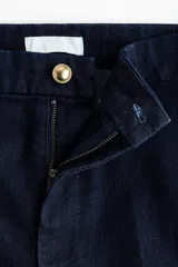 Jean acampanado de tiro alto en color azul marino, confeccionado en denim suave con leve elasticidad. Cuenta con cierre frontal y botón metálico.