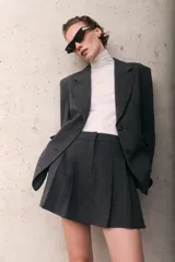 Blazer de mujer gris oscuro con estampado Príncipe de Gales (a cuadros). Presenta solapas de muesca, cierre frontal de dos botones, hombreras y bolsillos delanteros con solapa.