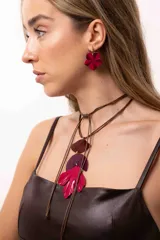 Collar ajustable con tres medallones texturados y pintados a mano en tonos borravino y fucsia, unidos por arandelas metálicas doradas y plateadas. Presenta un diseño versátil con tiento sintético que permite regular el largo y la posición de las tiras.