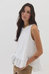 Top blanco de silueta suelta con cuello redondo, sin mangas y con volado asimétrico en el ruedo.