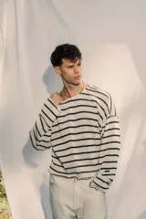 Sweater de tejido ligero a rayas horizontales blancas y negras, con cuello redondo y mangas largas. Presenta un pequeño bordado en la manga.