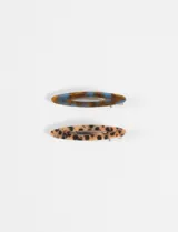 Set de dos horquillas para el pelo de forma ovalada, una con diseño marmolado en tonos azules y marrones, y otra con estampado animal print tipo leopardo.