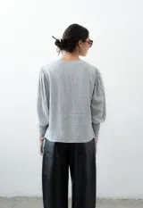 Blusa estampada en blanco y negro, con cuello redondo y mangas globo de puños elastizados largos. Presenta tiras ajustables en los laterales.