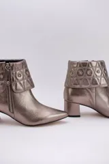 Botas cortas de cuero negro con taco cuadrado y punta fina. Presentan cuello caído capitoneado con apliques brillantes y cierre lateral con cremallera.