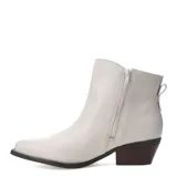 Botas de caña baja estilo texano, color blanco, con punta fina y taco cuadrado de madera. Presentan detalle de tachas metálicas en el lateral y cierre oculto.