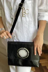 Sobre de mano color bordó en cuero charolado, con solapa frontal decorada con una piedra ágata natural engarzada. Incluye correa larga extraíble y cierre trasero.