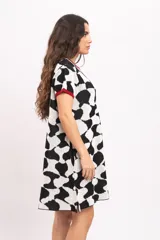 Vestido corto de tejido de punto con diseño abstracto en blanco y negro, mangas cortas y detalles en color rojo en el cuello y los puños.