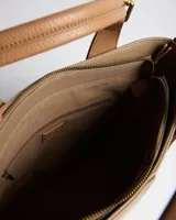 Cartera tipo tote XL de símil cuero con textura granulada en color verde, con dos asas de mano y correa bandolera regulable y desmontable en tono suela. Cuenta con cierre superior, costura central decorativa y parche frontal con logo en relieve.