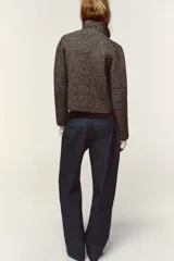 Chaqueta de punto con textura jaspeada, cuello solapa y manga larga. Presenta bolsillos delanteros de plastrón con solapa y cierre frontal con botones forrados a tono.