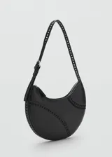 Bolso de hombro tipo media luna en color negro, con diseño minimalista y detalles de costuras decorativas perforadas en la parte frontal. Cuenta con una correa ajustable con hebilla y cierre superior.