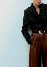 Pantalón de corte wide leg, confeccionado en material sintético efecto cuero color marrón, con pinzas en la cintura y bolsillos laterales.