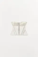 Corsé blanco de escote corazón y hombros descubiertos, confeccionado con copas de encaje y cuerpo de tejido de malla transparente con varillas interiores y cierre frontal de ganchos metálicos.