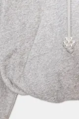 Sudadera de corte holgado con capucha ajustable mediante cordones con detalle de perlas en los extremos. Presenta mangas largas con puños elásticos y bajo con acabado tipo globo.