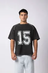 Remera de algodón con efecto de lavado gastado, corte holgado y diseño deportivo. Presenta el número 15 estampado en el frente con acabado desgastado y detalles de costuras blancas en los hombros y laterales.