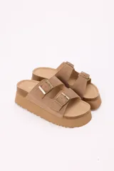 Sandalias planas color marrón con plataforma de goma y doble tira con hebillas metálicas ajustables.