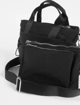 Bandolera color beige con asas negras y correa regulable extraíble. Cuenta con un estuche frontal removible, bolsillos laterales de malla con cordón ajustable, doble cierre y un bolsillo delantero.