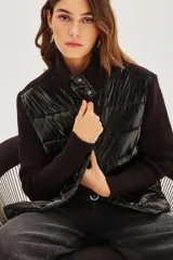 Campera híbrida de diseño moderno, con frente acolchado tipo puffer en acabado brillante y mangas tejidas en punto acanalado. Presenta cuello alto tejido y cierre frontal con botones a presión.