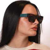 Lentes de sol con armazón cuadrado de acetato en color negro con efecto marmolado en las patillas y cristales tintados en color violeta. Cuentan con protección UV400.