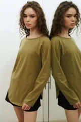 Remera de manga larga estilo raglan, color verde militar, con cuello redondo y dobladillo inferior curvado.