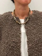 Collar de cuentas de piedras naturales en tonos tierra, con detalles de tubos dorados en los laterales.