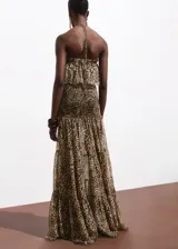 Vestido maxi largo de chifón con estampado animal print de leopardo. Presenta cuello halter con cierre de nudo, escote palabra de honor con gran volante superior y cuerpo elástico fruncido.